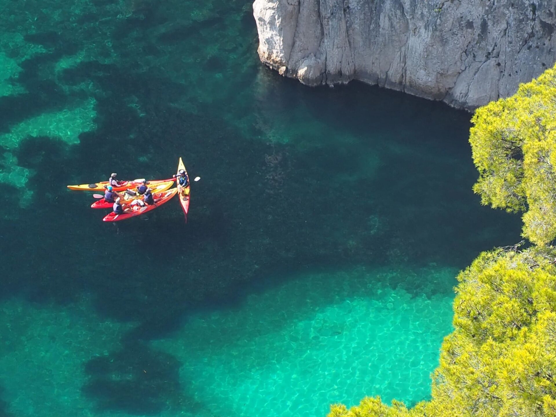 Personas haciendo kayak en las Calanques de Marsella, rodeadas de acantilados y aguas cristalinas.