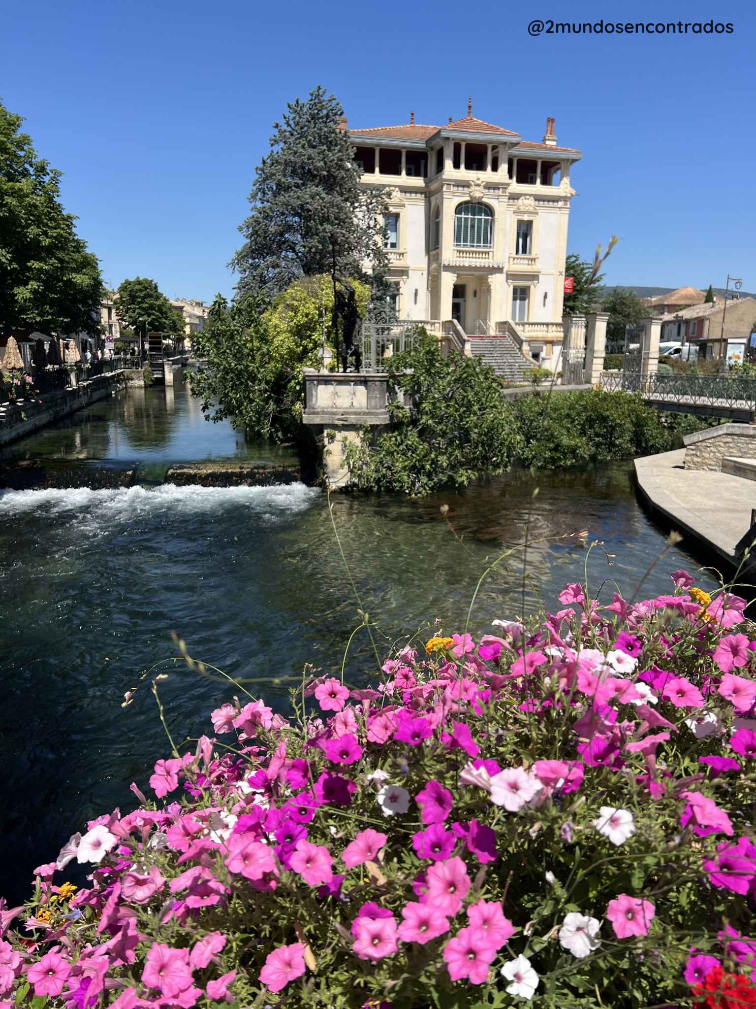 Canal de L'Isle-sur-la-Sorgue con flores en primer plano y una elegante villa junto al río Sorgue, en la Provenza francesa. Qué ver en la Provenza en 11 días