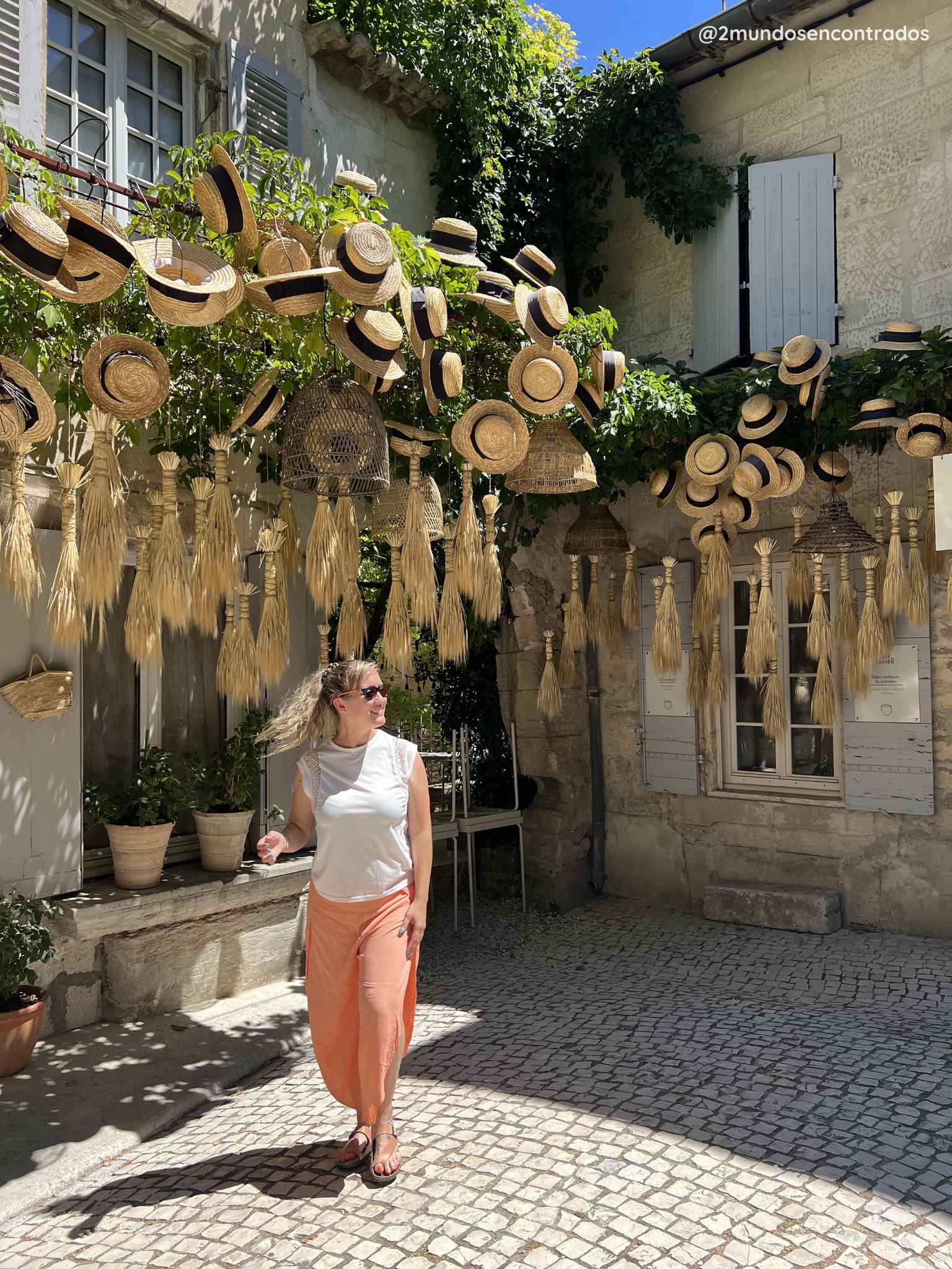Eva paseando bajo una decoración de sombreros de paja en una calle del centro histórico de Saint-Rémy-de-Provence, Francia.