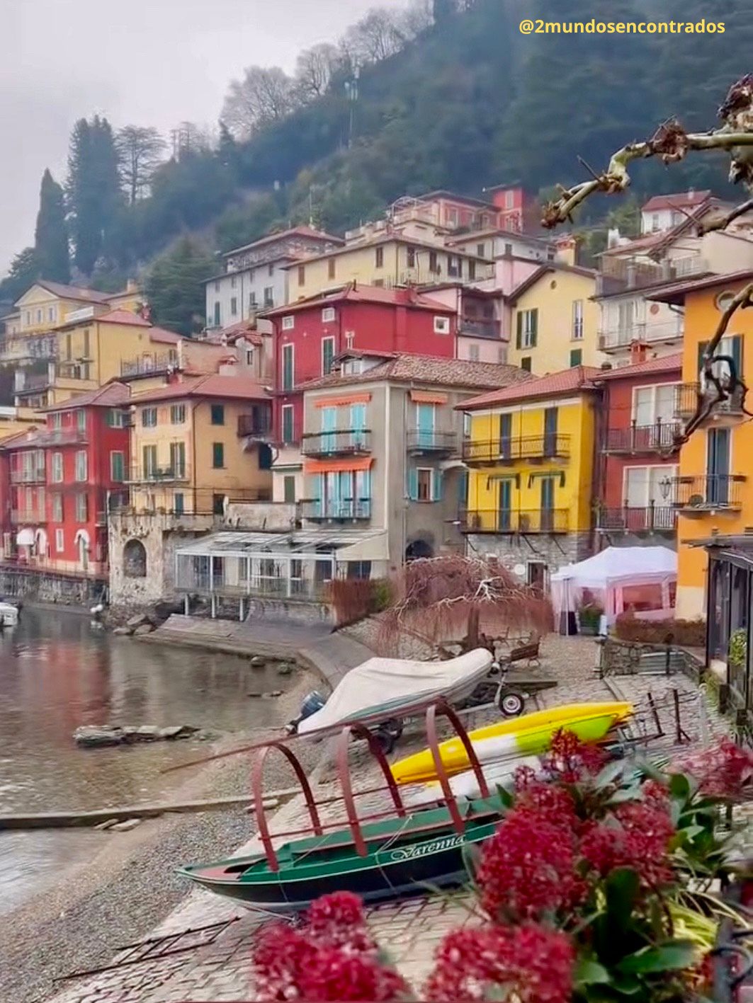 Pueblo del lago de Como con casas de colores junto al agua y montañas al fondo.