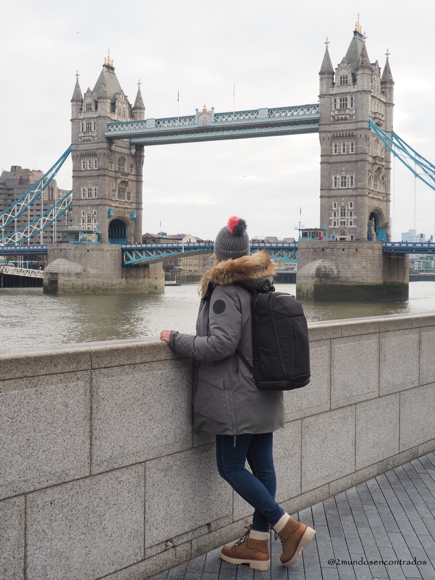 Persona de espaldas mirando el Tower Bridge desde la ribera del TĂĄmesis.