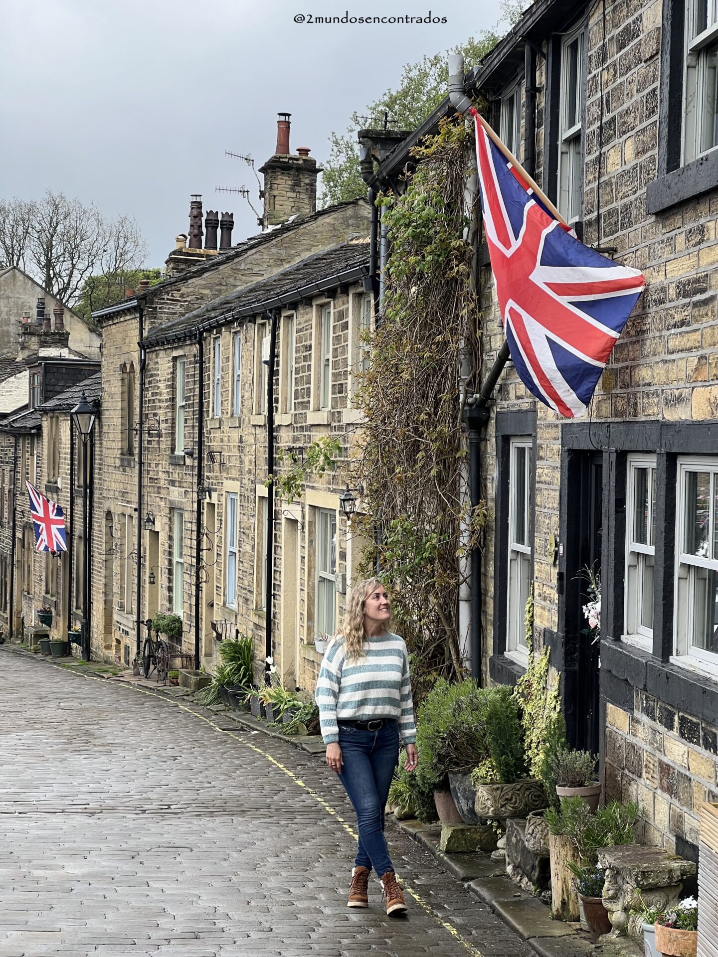 Calle histórica de Haworth con una bandera del Reino Unido ondeando entre edificios de piedra tradicionales.