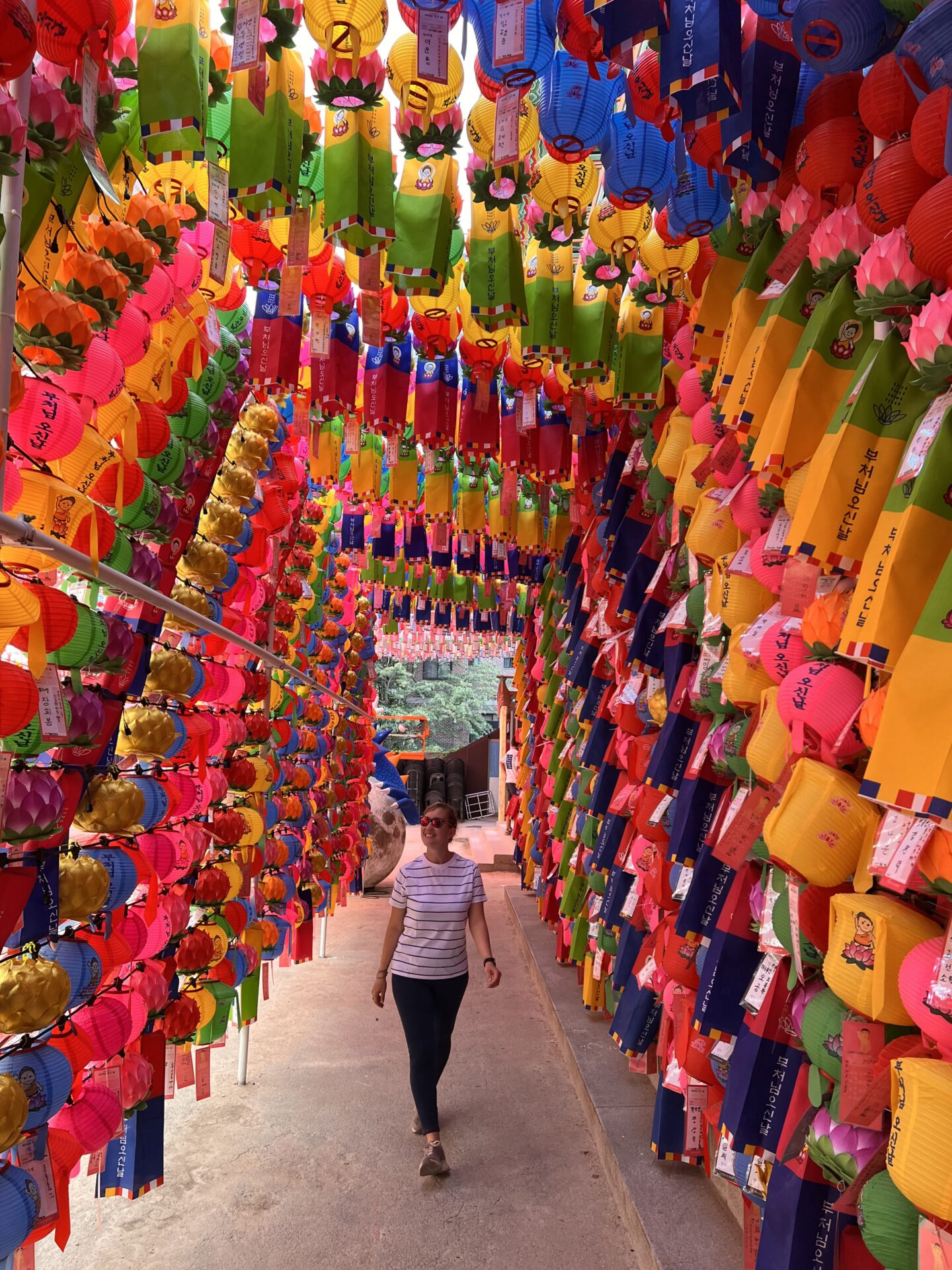 Visitante caminando bajo un techo de coloridos faroles de papel en el templo Jogyesa de Seúl, Corea del Sur.