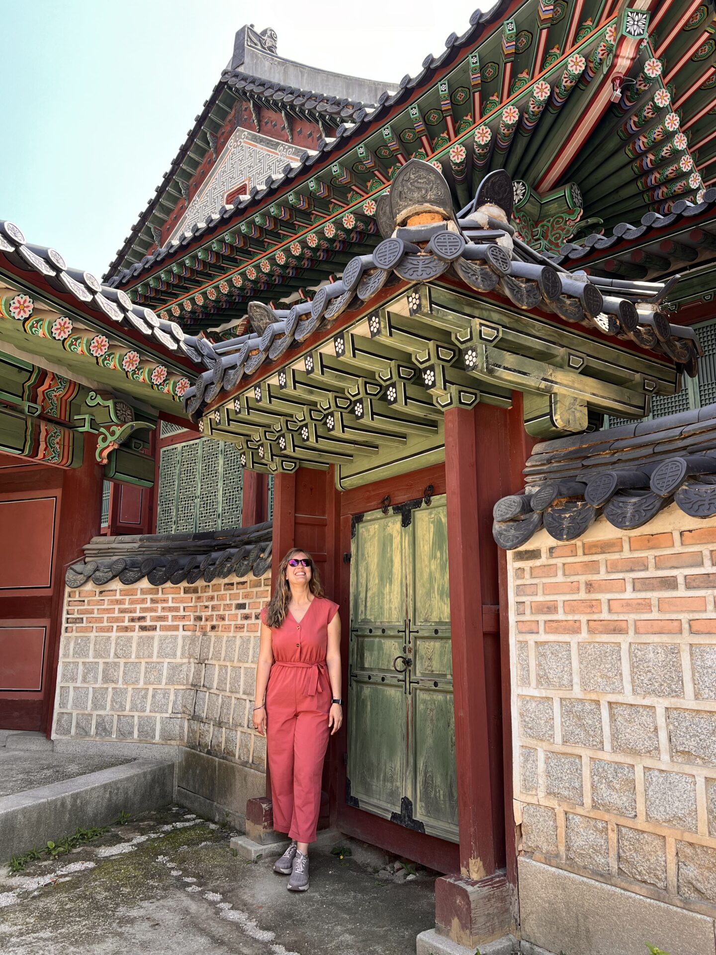 Visitante junto a una puerta y tejados decorados del Palacio Gyeongbokgung en Seúl.