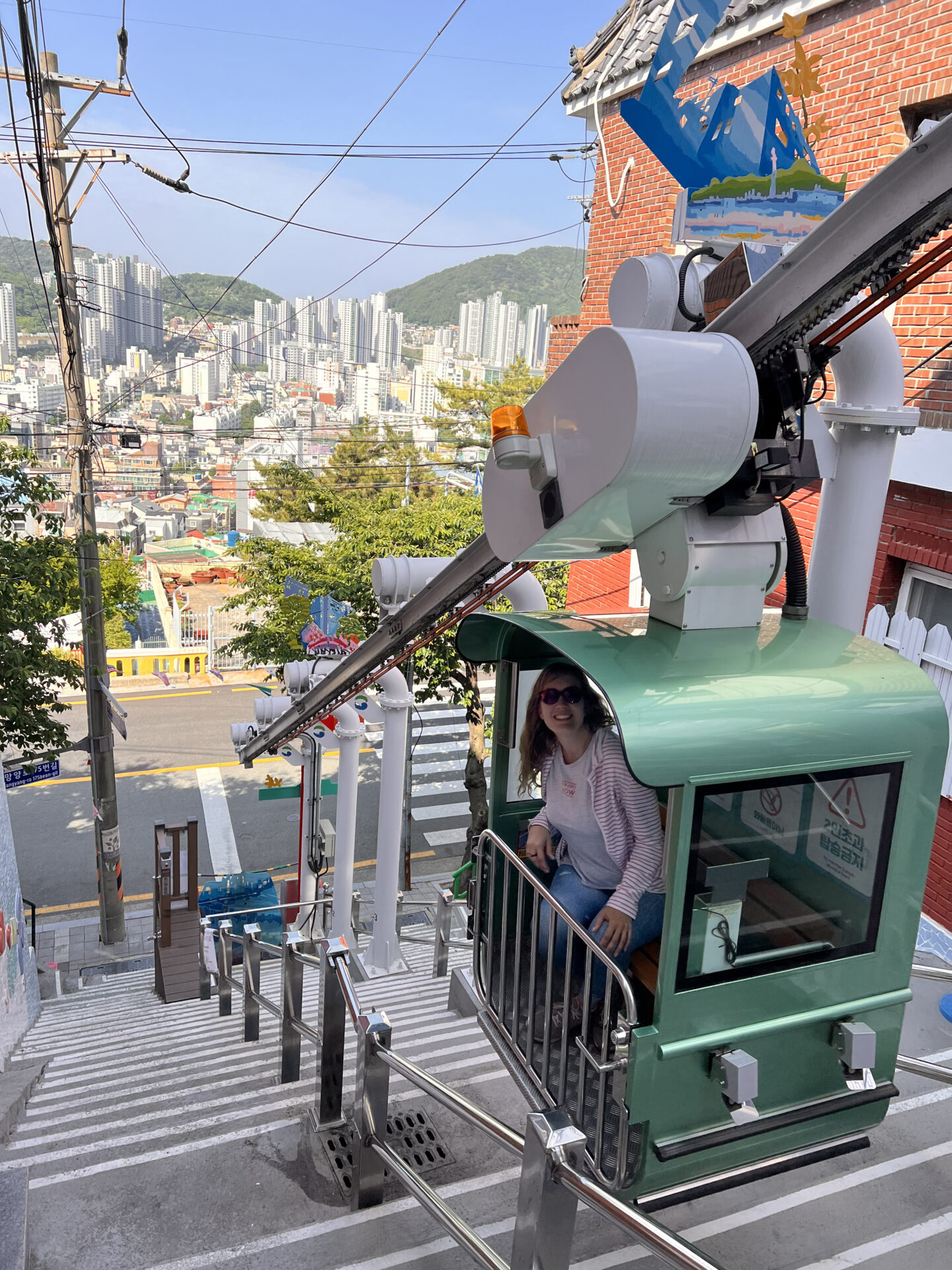 Songdo Sky Capsule descendiendo por la ladera con vistas panorámicas de Busan y sus edificios residenciales.