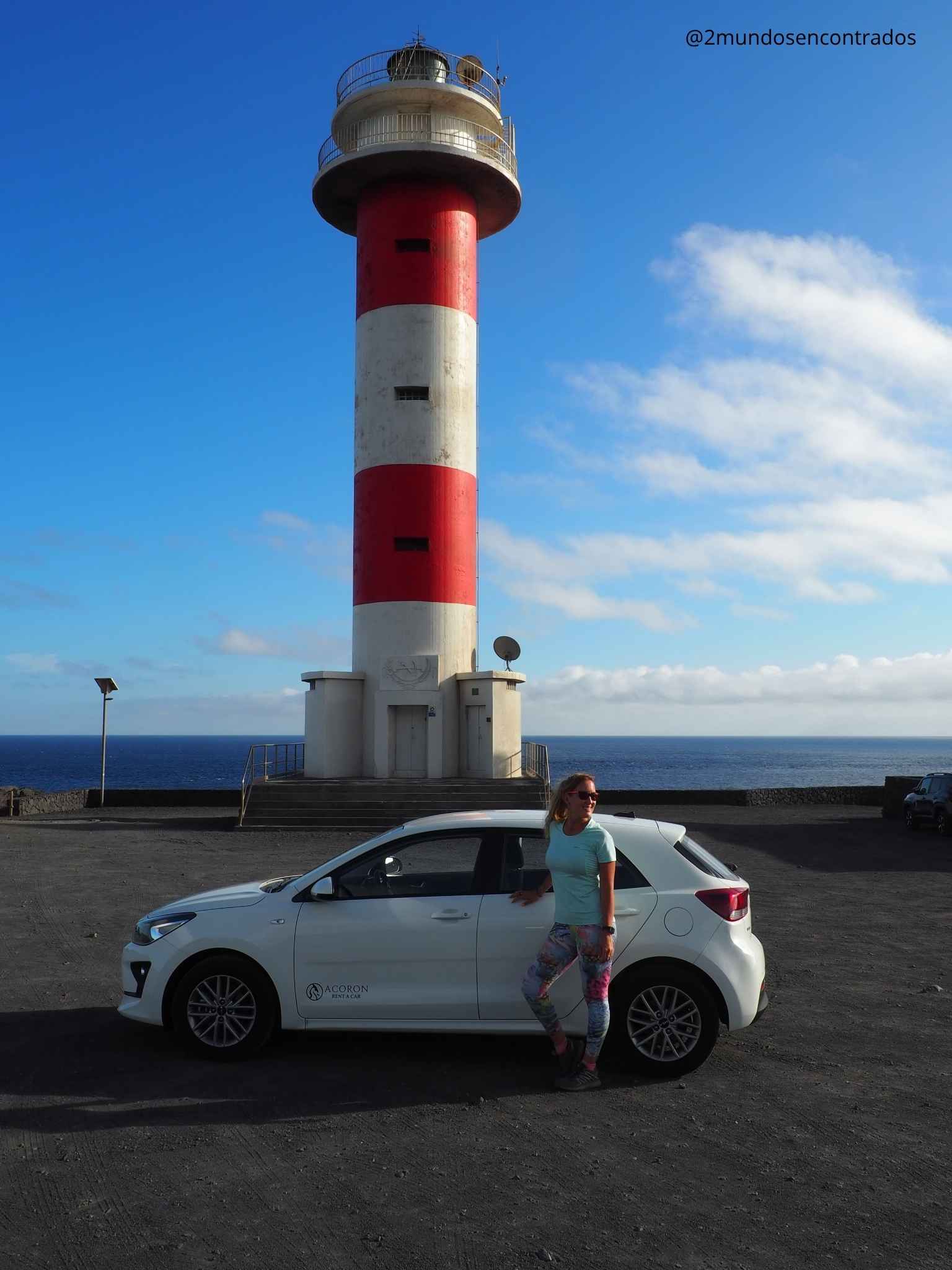 Eva posando junto a un coche de alquiler frente al faro rojo y blanco de Fuencaliente en La Palma. Qué ver en La Palma en 5 días