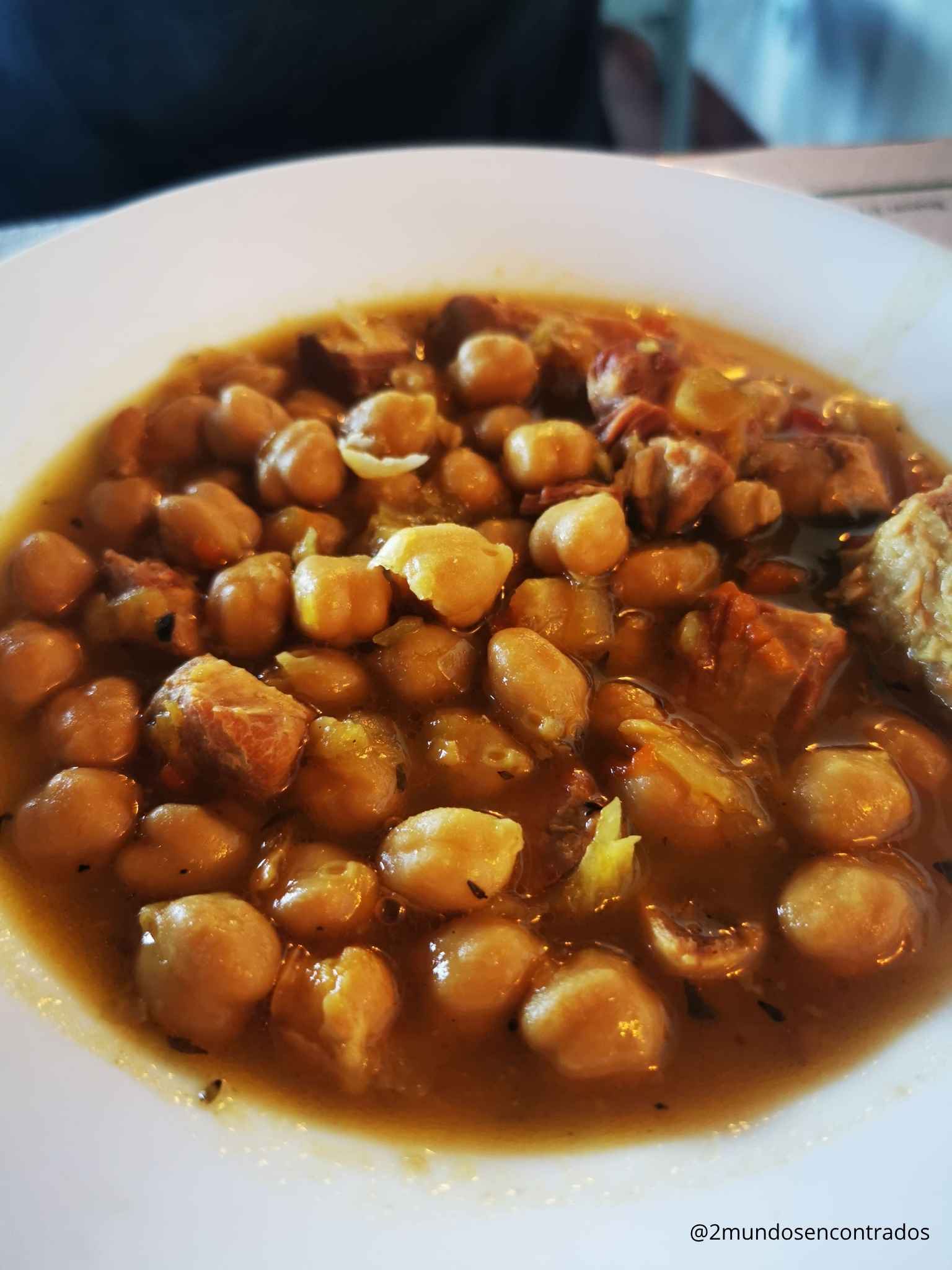 Plato hondo con guiso tradicional de garbanzos estofados con trozos de carne.