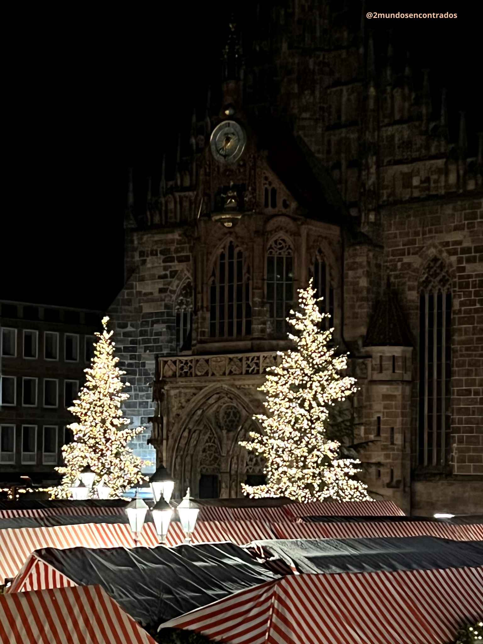 Mercado de Navidad de Núremberg con la iglesia de San Lorenzo iluminada durante la noche.