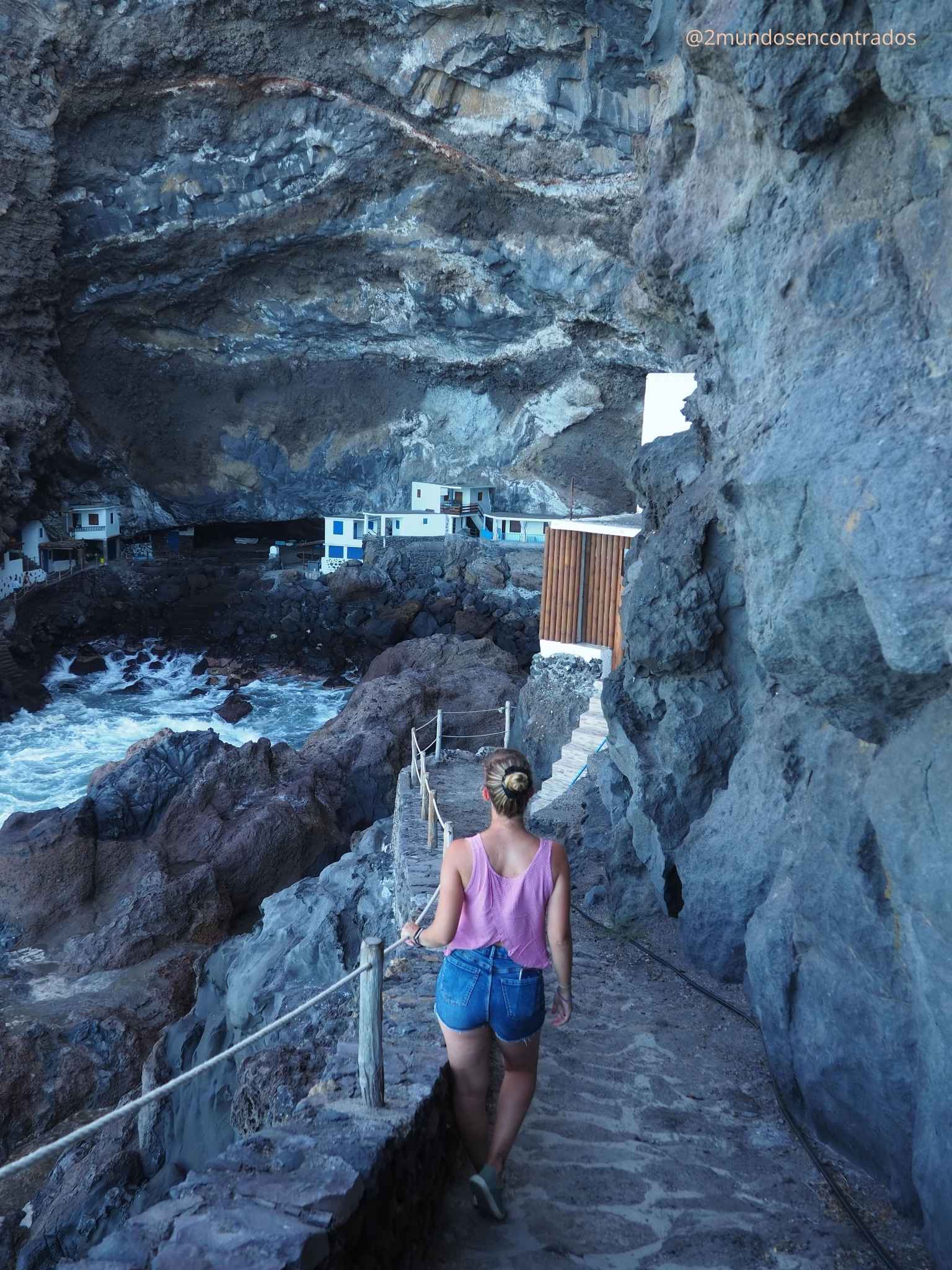 Mujer caminando hacia las casas blancas construidas dentro de una cueva volcánica en el Porís de Candelaria, La Palma.