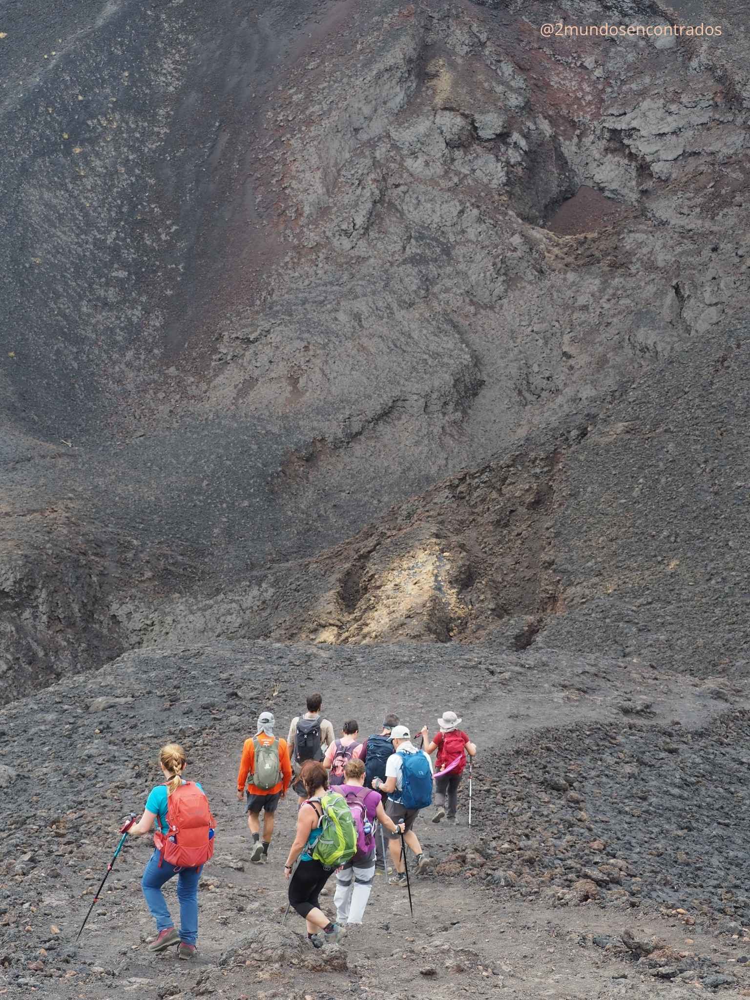 Grupo de senderistas caminando con mochilas por un sendero de tierra y picón volcánico en La Palma.
