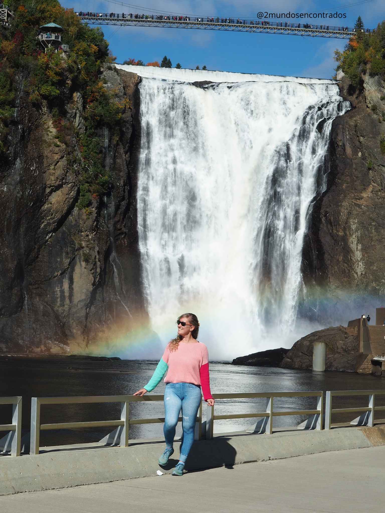 Eva posando frente a la gran cascada Chute Montmorency con un arcoíris en la base.