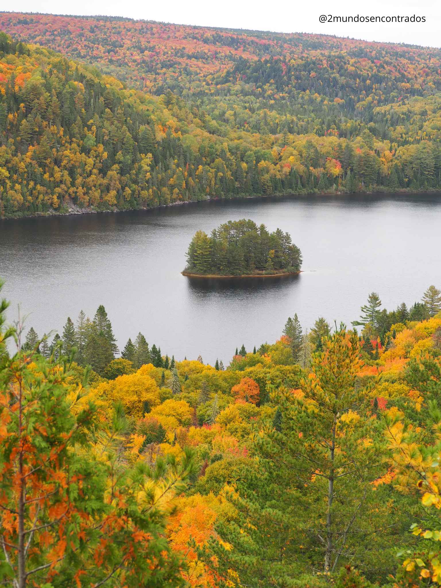 Vista panorámica de una pequeña isla en el lago Lac Solitaire rodeada de bosques de otoño.